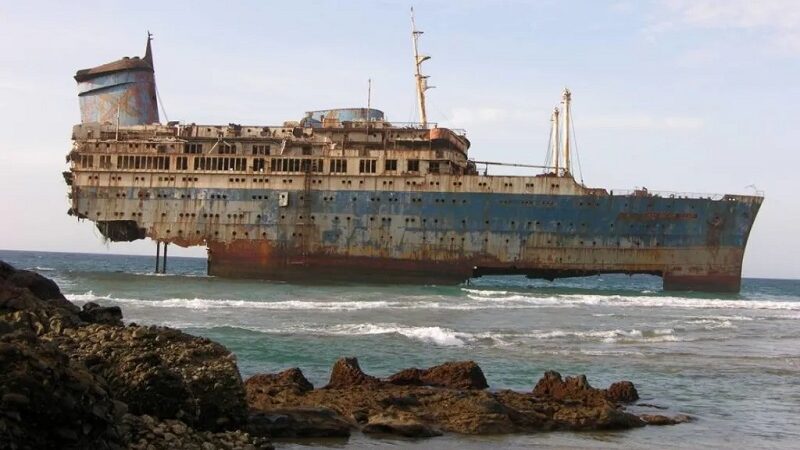 A rusty old ship on the surface of the ocean.